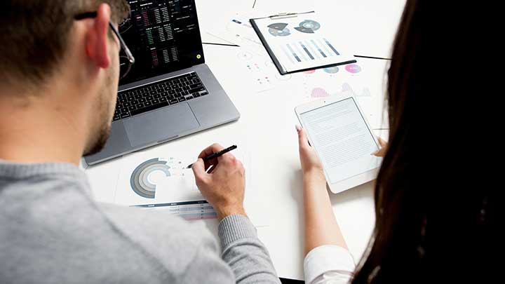 Zwei Personen arbeiten zusammen an einem Laptop und einem Tablet